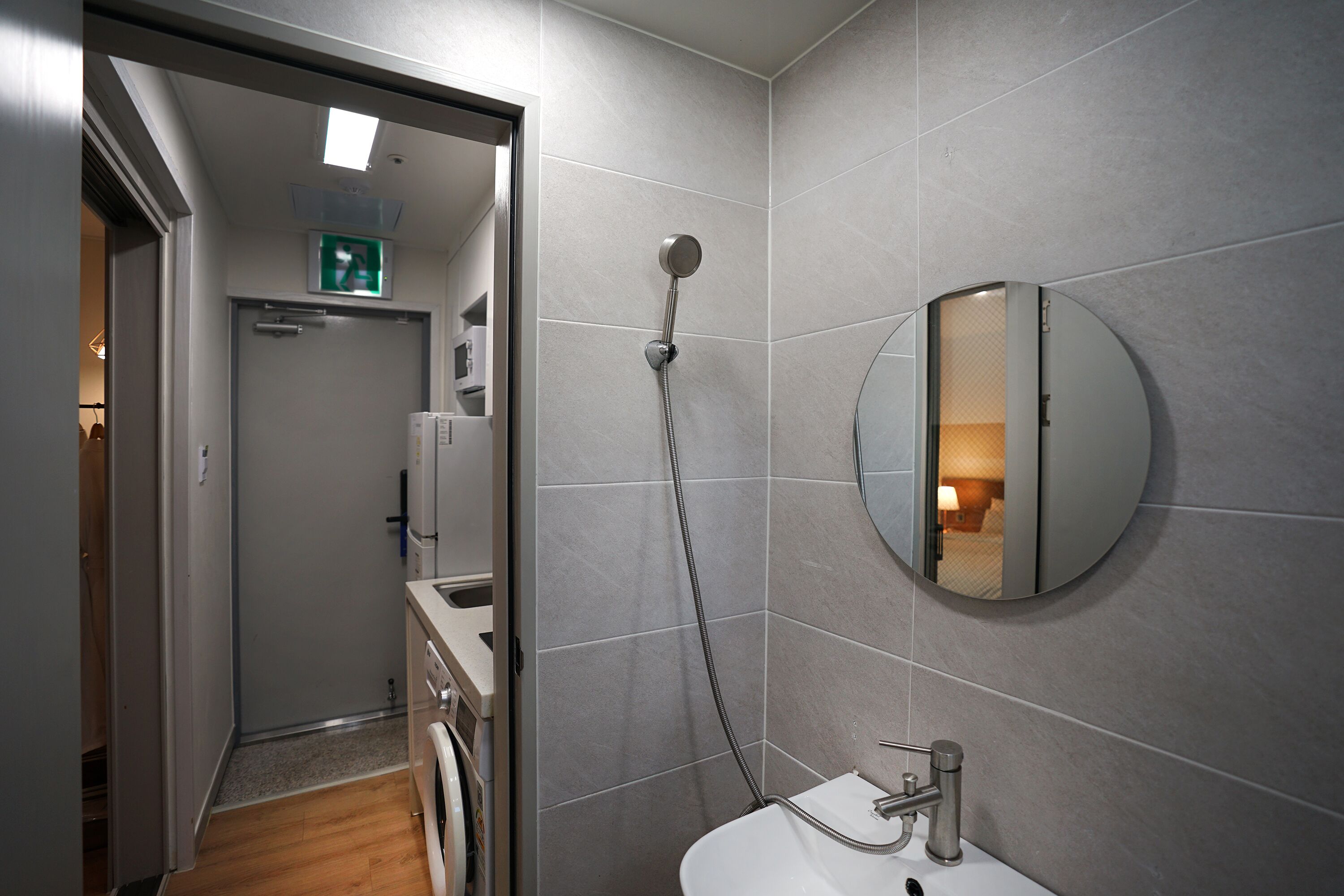 A modern bathroom with a shower, sink, and a round mirror on the wall.