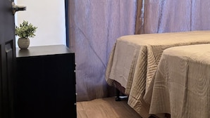 Una camera da letto con un letto, una cassettiera e una tenda.