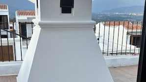 Una terrazza sul tetto con una struttura bianca, pavimento in legno e vista su montagne lontane.