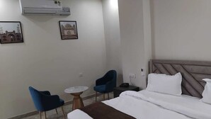 A hotel room with a bed, two chairs, a small round table, and two wall-mounted air conditioning units. - Hotel Fortune Elevate (Jaipur)