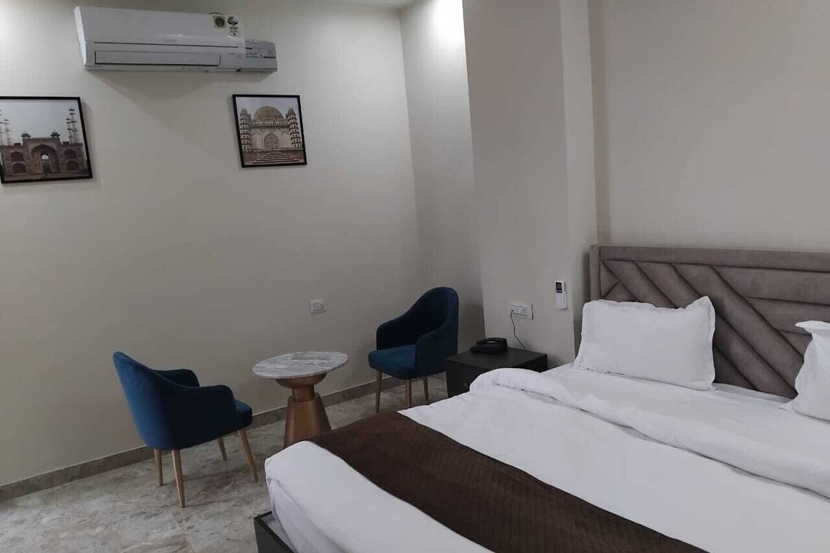 Ein Hotelzimmer mit einem Bett, zwei Stühlen, einem runden Tisch und zwei Wandklimageräten.