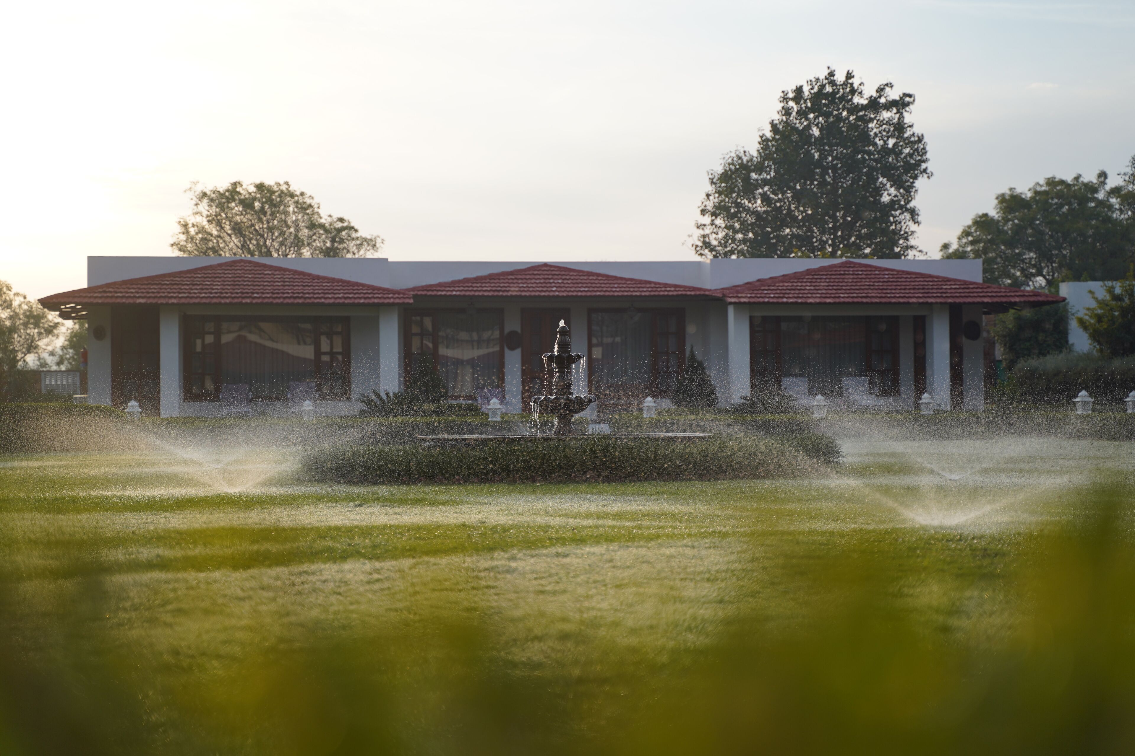 Een gebouw met een symmetrische gevel, een centrale fontein en een verzorgd gazon.