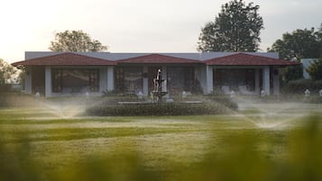 Een gebouw met een symmetrische gevel, een centrale fontein en een verzorgd gazon.