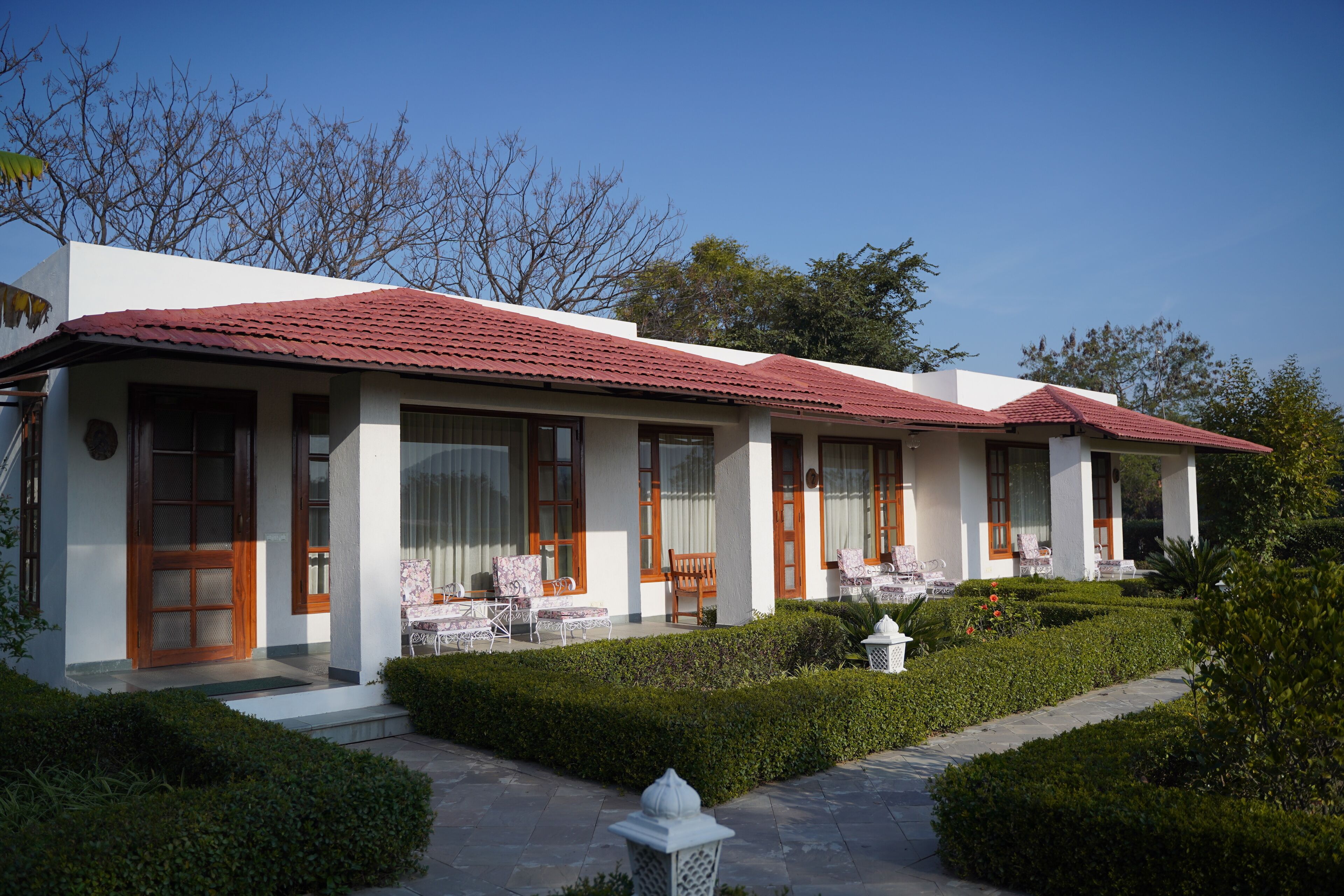 A two-story building with a red-tiled roof, large windows, and a well-maintained garden.