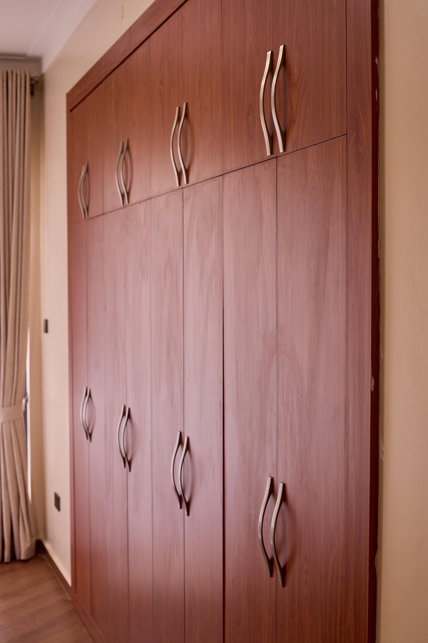 Ein hölzerner Kleiderschrank mit mehreren Türen und gebogenen Griffen.