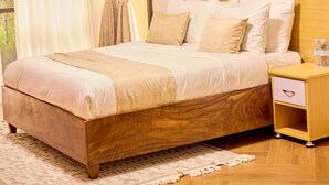 Un letto ben rifatto con una testiera in legno, un comodino con un cassetto e un quadro appeso al muro.