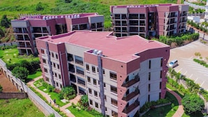 Un edificio residenziale a più piani con tetto piatto, numerosi balconi e un’area di parcheggio.
