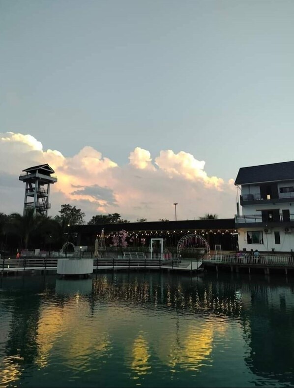 Une zone riveraine avec une tour, un bâtiment doté d’un balcon et son reflet dans l’eau.
