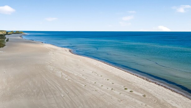 Una playa con aguas azules cristalinas y una orilla arenosa.