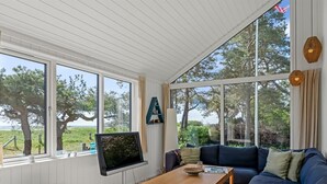 Un salón acogedor con un gran ventanal, un televisor, un sofá y una mesa de centro de madera.