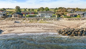 Une propriété située sur la côte, comprenant plusieurs maisons, un littoral rocheux et un ciel dégagé.