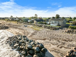 Une propriété située sur la côte, dotée d’une plage de sable, d’un rivage rocheux et de plusieurs maisons à l’architecture moderne.