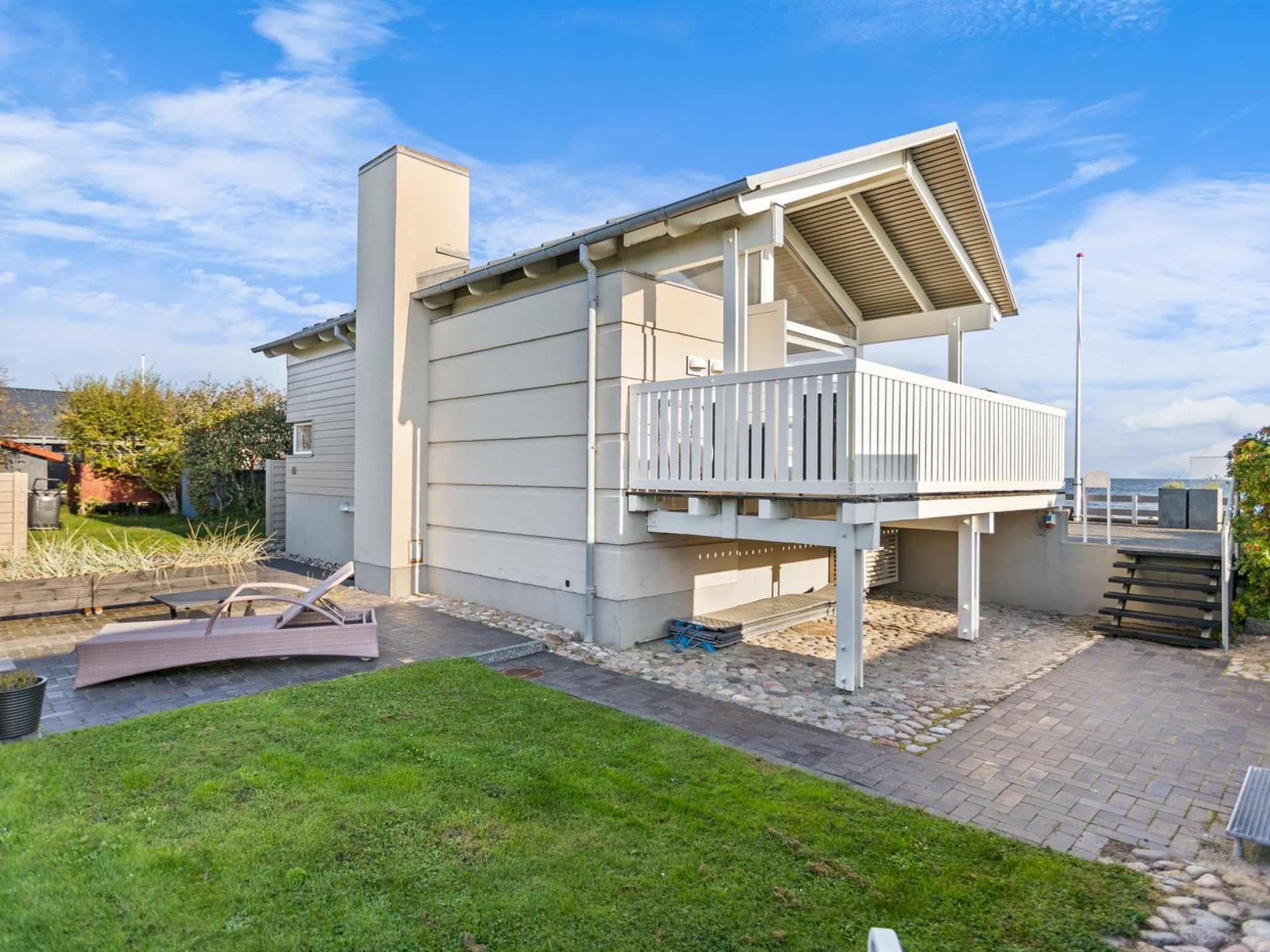 Ein modernes, zweistöckiges Haus mit Balkon, Garage und gepflegtem Rasen.