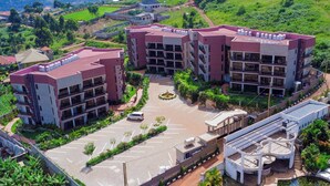 A multi-story building with a parking lot and a landscaped area. - Sand Grains Residences 007 (Entebbe)