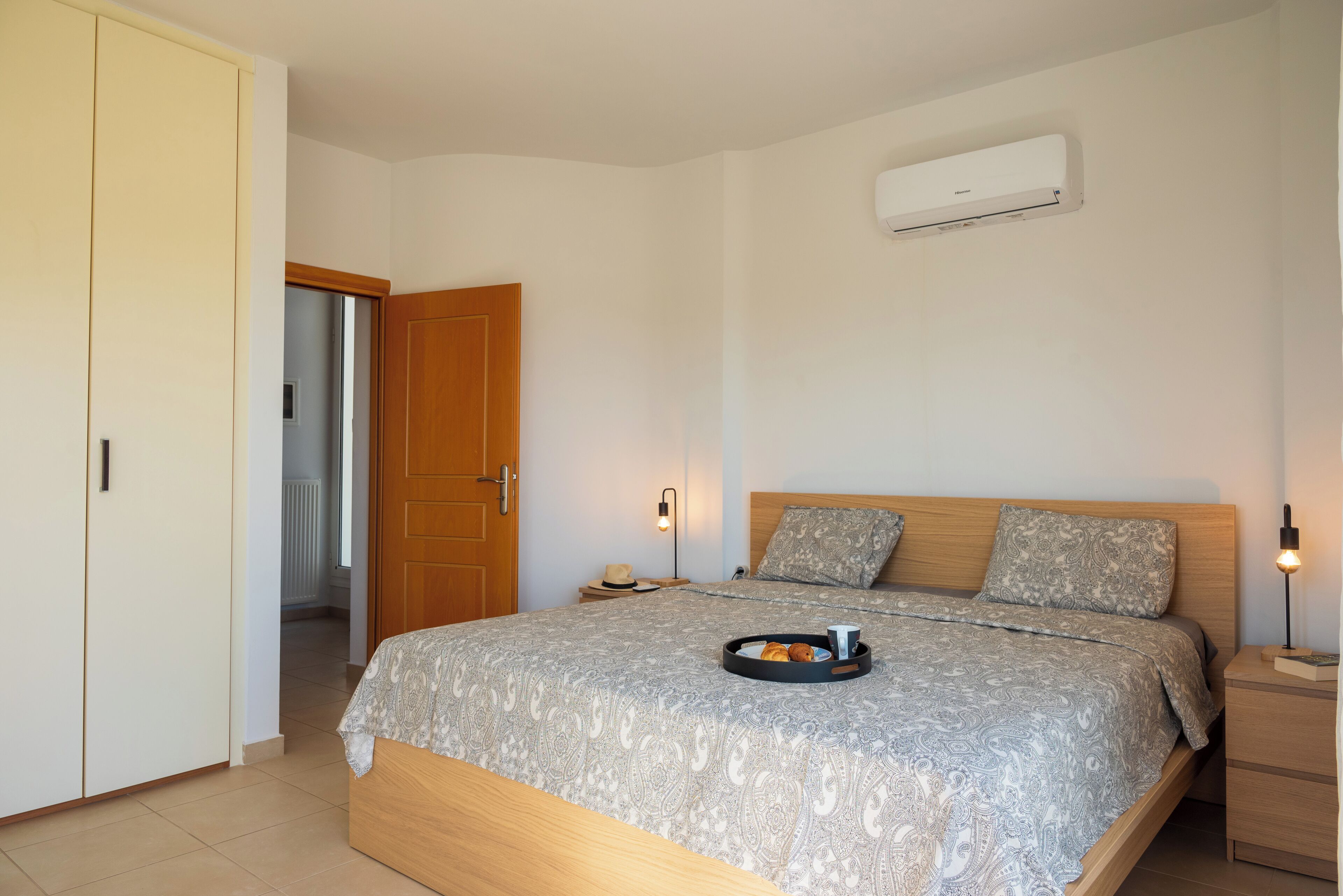 Ein Schlafzimmer mit Bett, Nachttischen, einer Klimaanlage und einem Kleiderschrank.