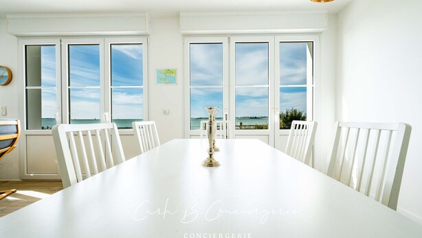 A dining room with a long white table, white chairs, and a view of the sea through large windows. - Beachfront villa. Exceptional view.Sleeps 8 (Gâvres)