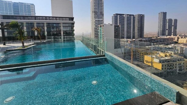 Une piscine sur le toit offrant une vue panoramique sur la ville, entourée d’immeubles modernes.