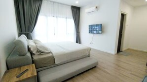 Een slaapkamer met een bed, een bank, een televisie en een plafondventilator.