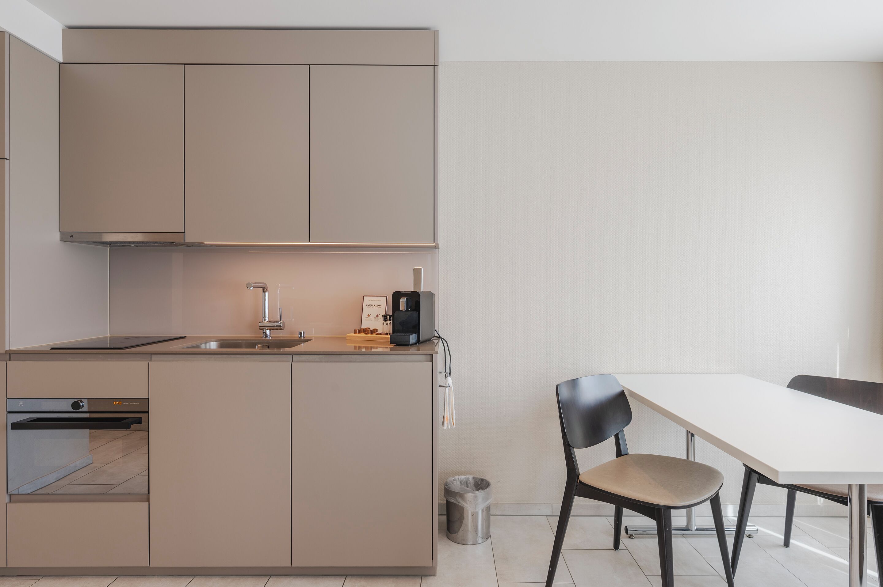 Una cocina moderna con horno integrado, cafetera y lavamanos.