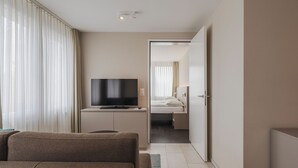 Una habitación de hotel moderna con televisión de pantalla plana, un sofá, una cama y un vestidor.