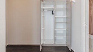 Un vestidor con puerta de espejo y varios estantes.
