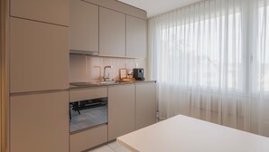 Una cocina moderna con electrodomésticos integrados, un ventanal con cortinas ligeras y un diseño minimalista.