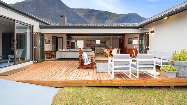 Ein modernes Haus mit Terrasse, Sitzgelegenheit im Freien und Blick auf die Berge.
