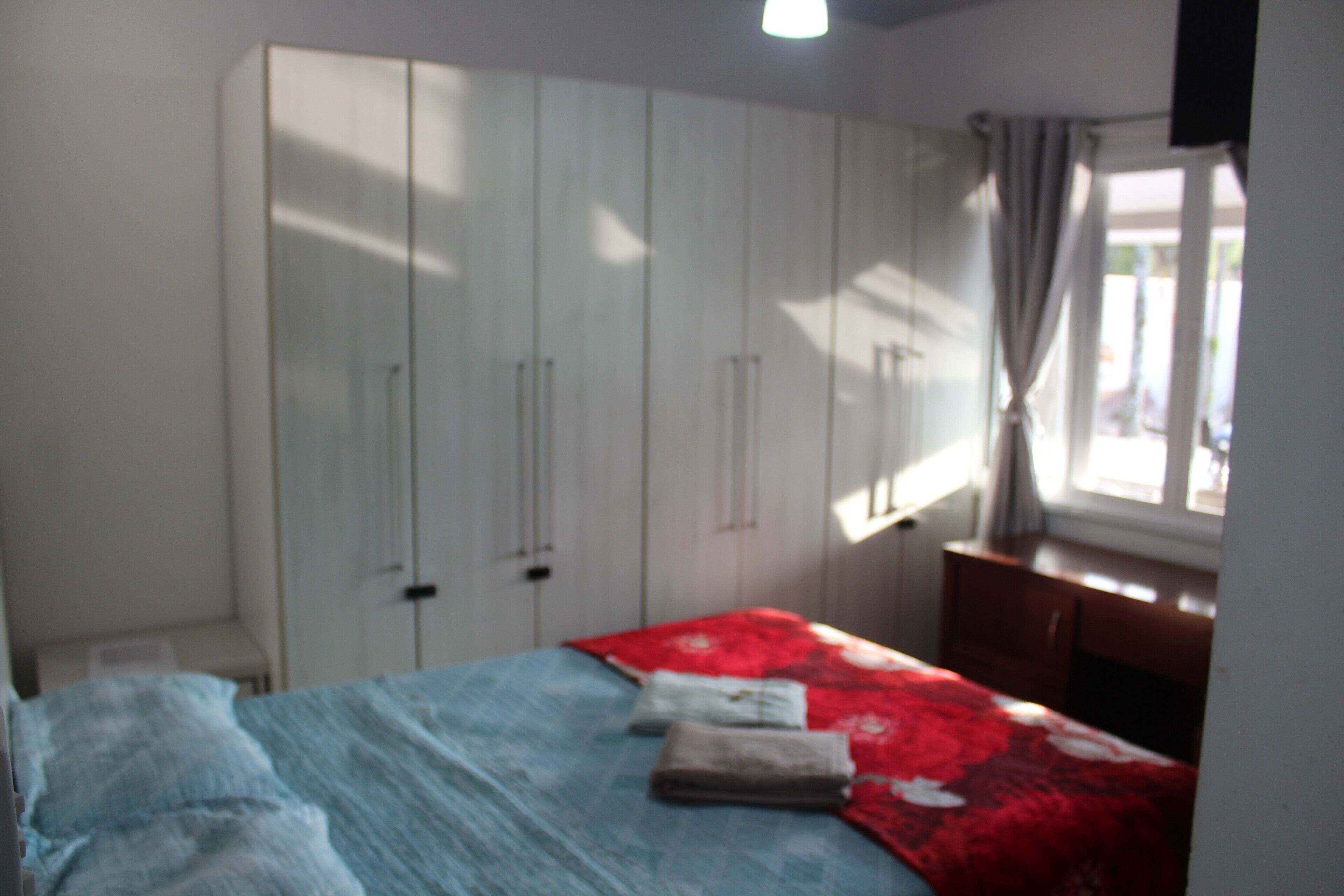 A bedroom with a bed, a wardrobe, and a window with curtains.