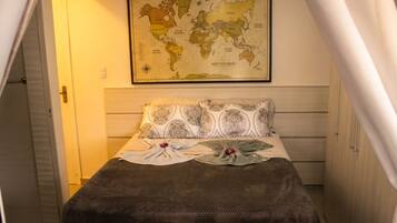 A bedroom with a bed, pillows, a map on the wall, and a door.