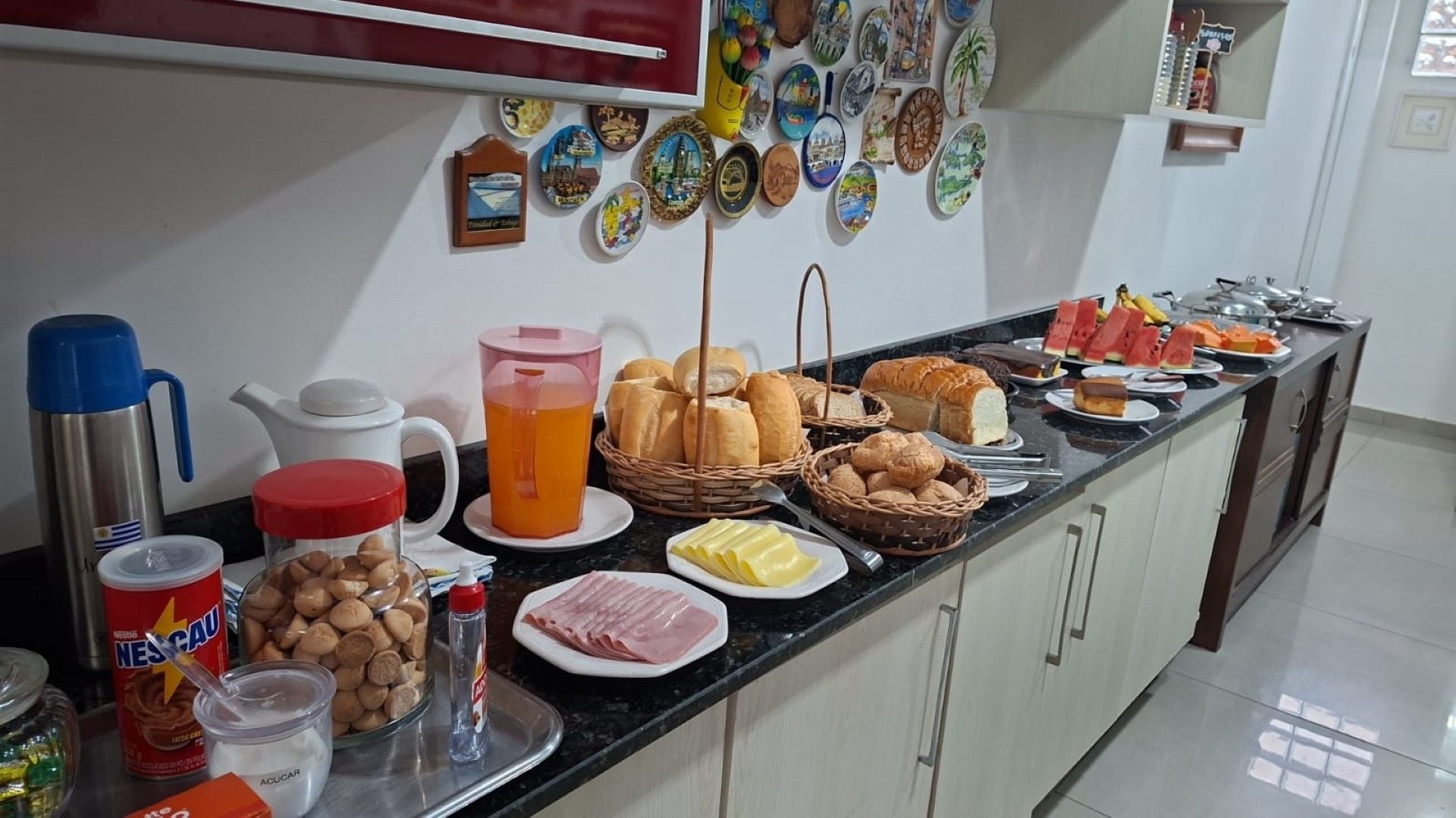 Un buffet de petit-déjeuner proposant divers aliments, une machine à café et des assiettes décoratives accrochées au mur.