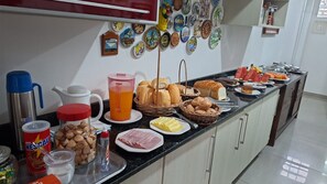 A breakfast buffet with various food items, a coffee maker, and decorative plates on the wall. - Pousada Captain Morgan (Pontal do Parana)