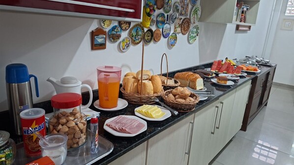 A breakfast buffet with various food items, a coffee maker, and decorative plates on the wall. - Pousada Captain Morgan (Pontal do Parana)