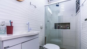 A modern bathroom with a white vanity, a glass shower enclosure, and a toilet. - Pousada Captain Morgan (Pontal do Parana)