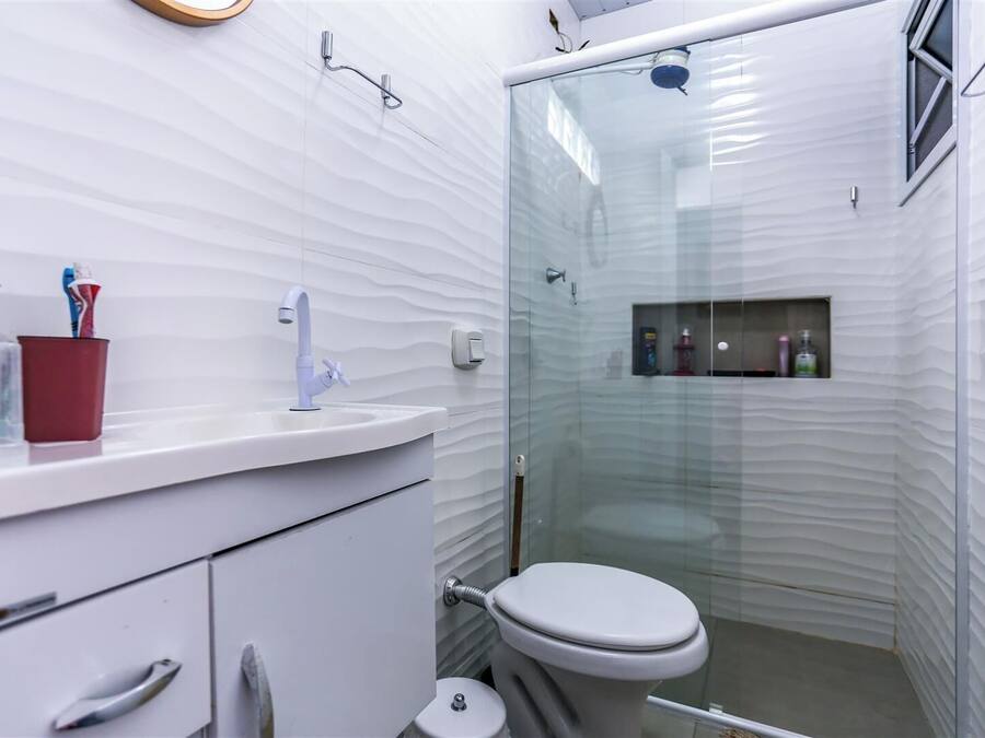 A modern bathroom with a white vanity, a glass shower enclosure, and a toilet.