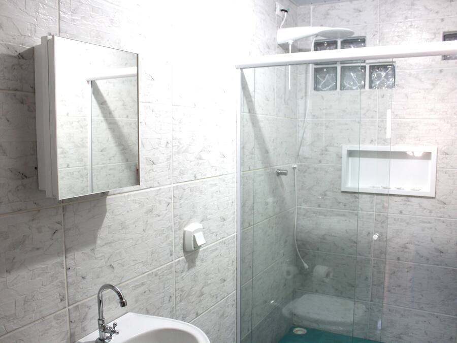A bathroom with a glass-enclosed shower, a sink, and a mirror.
