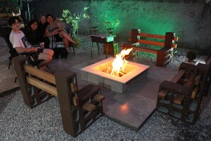 An outdoor seating area with a fire pit, wooden benches, and potted plants. - Pousada Captain Morgan (Pontal do Parana)