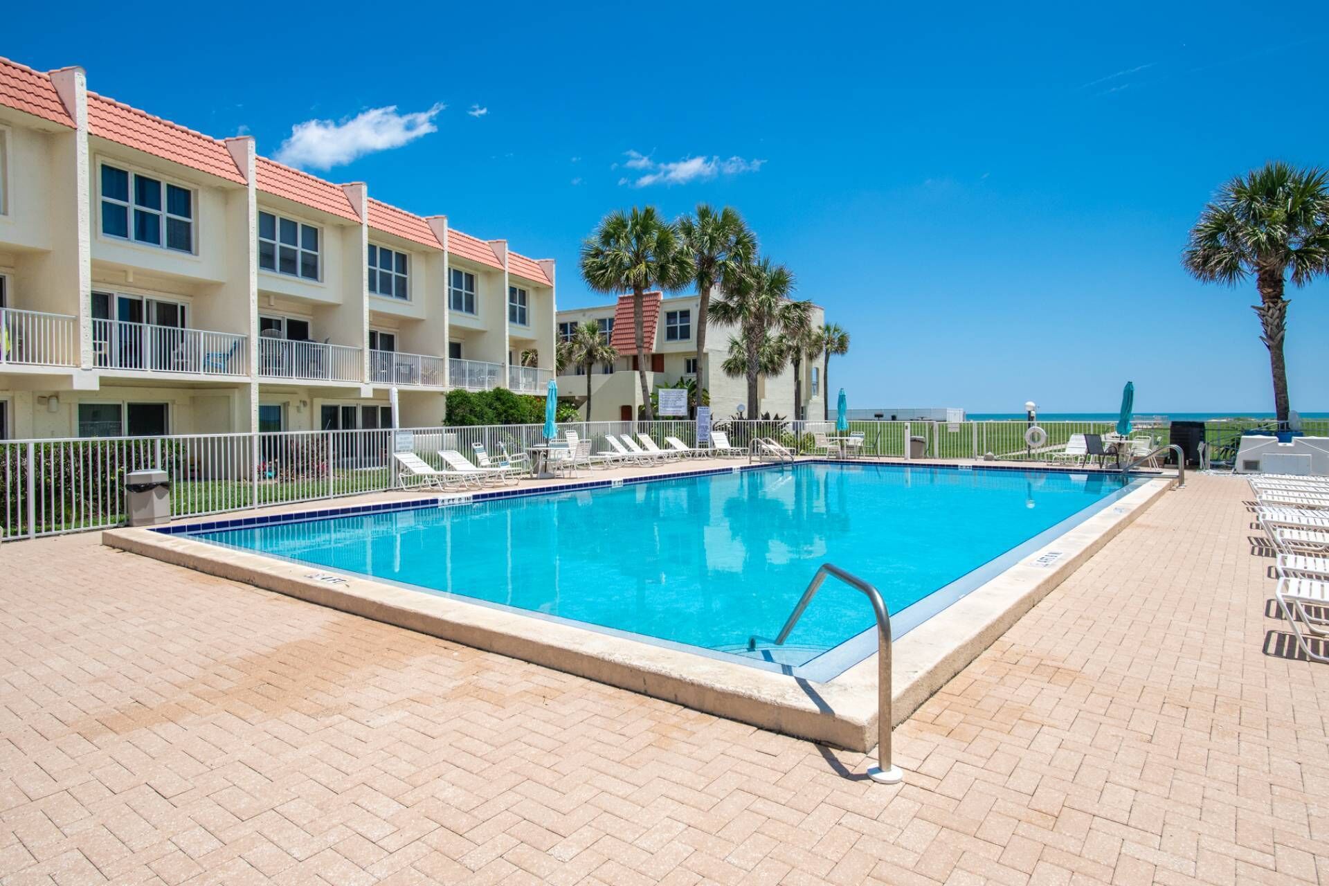 A rectangular swimming pool with a metal ladder, surrounded by a brick deck.