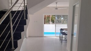 A modern interior with a staircase, a dining area, and a view through a glass door. - Tropical Paradise Villa in Sosua (Sosúa)