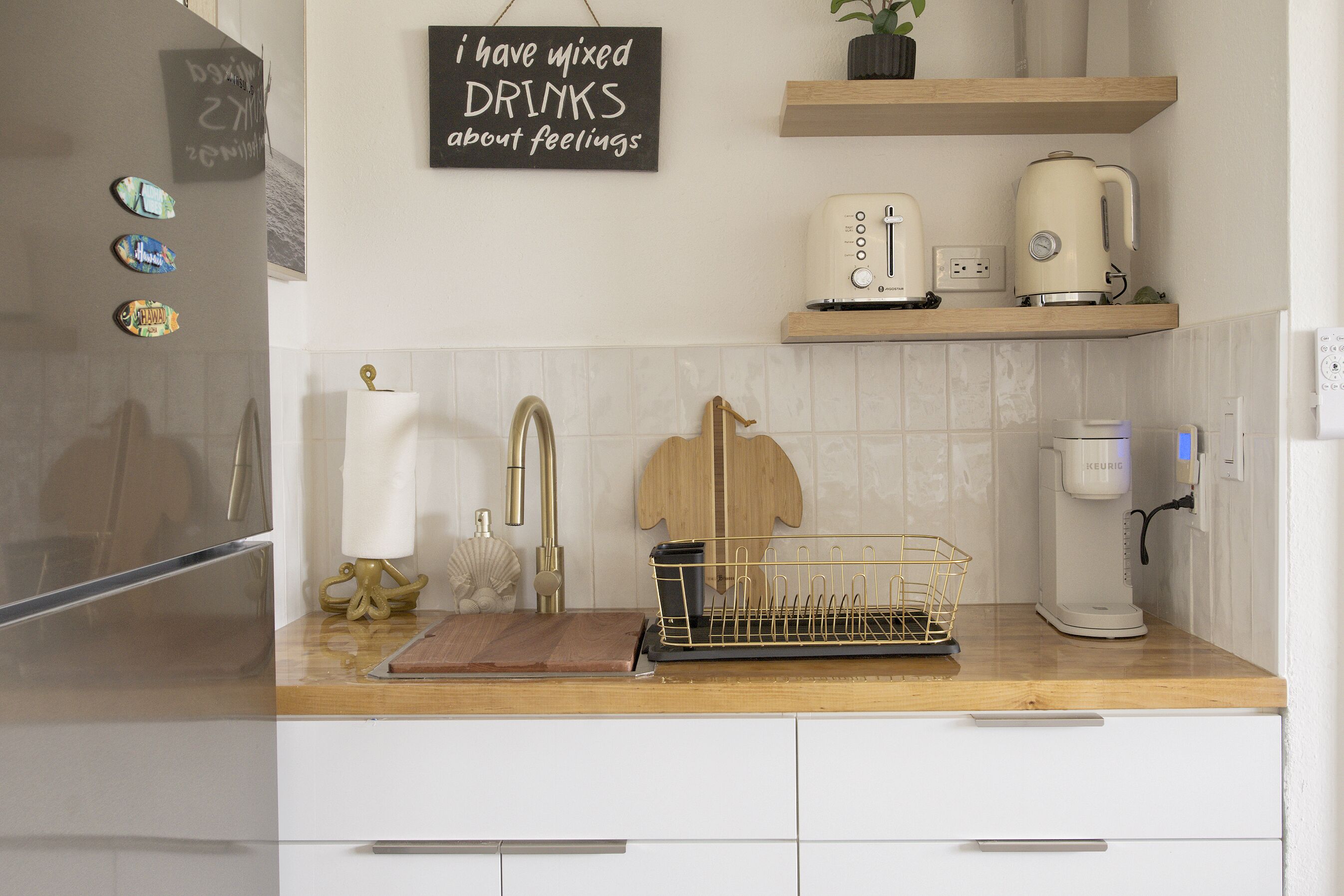 A kitchen with a wooden countertop, a sink, a kettle, a toaster, and a coffee maker.
