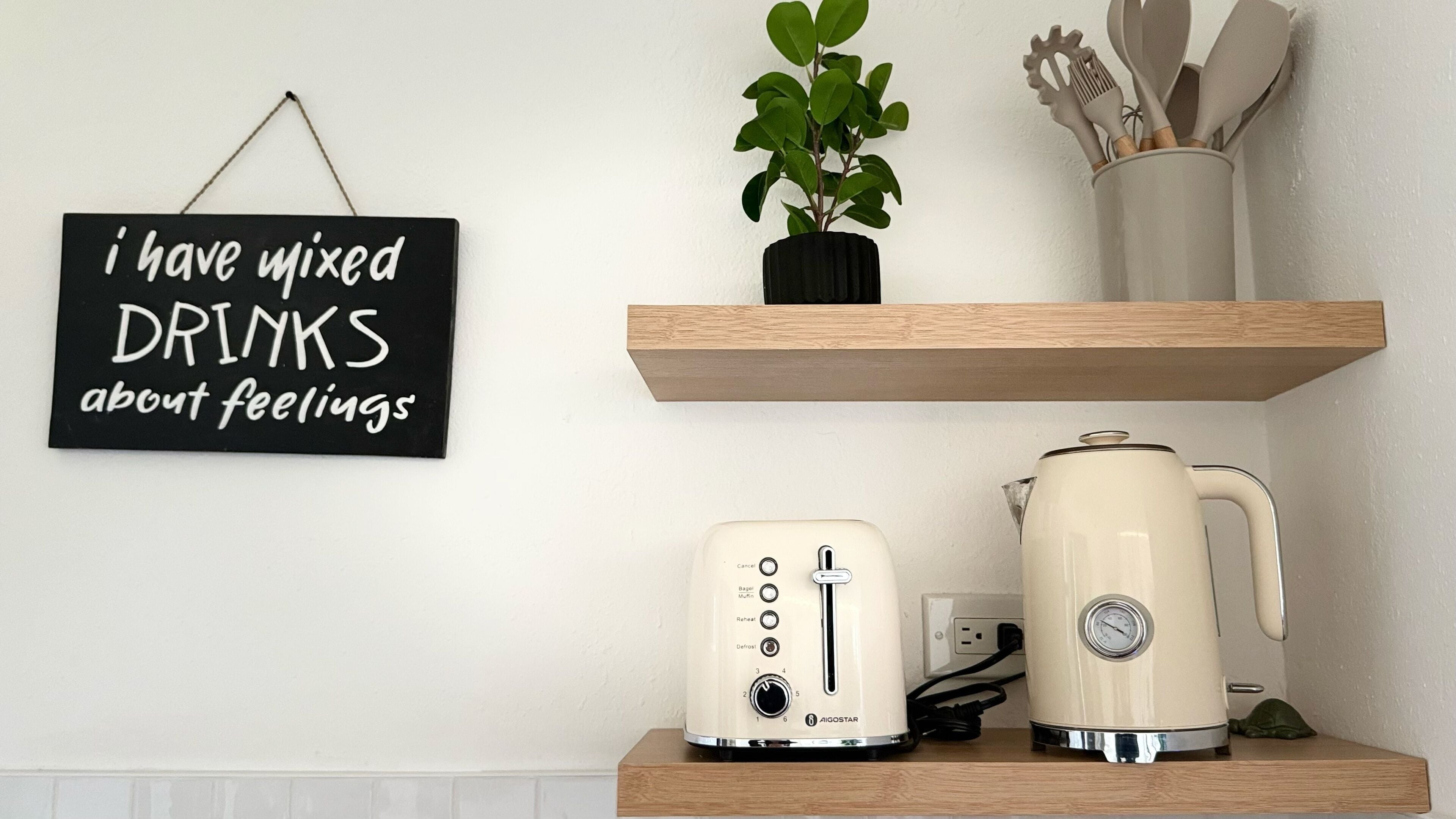 A kitchen counter with a toaster, a kettle, and a sign that reads "I have mixed DRINKS about feelings."