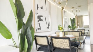 A modern dining area with a glass table, black and beige chairs, and large abstract paintings on the wall. - Honolulu Central Waikiki luxury High With Views & Beach (Honolulu)