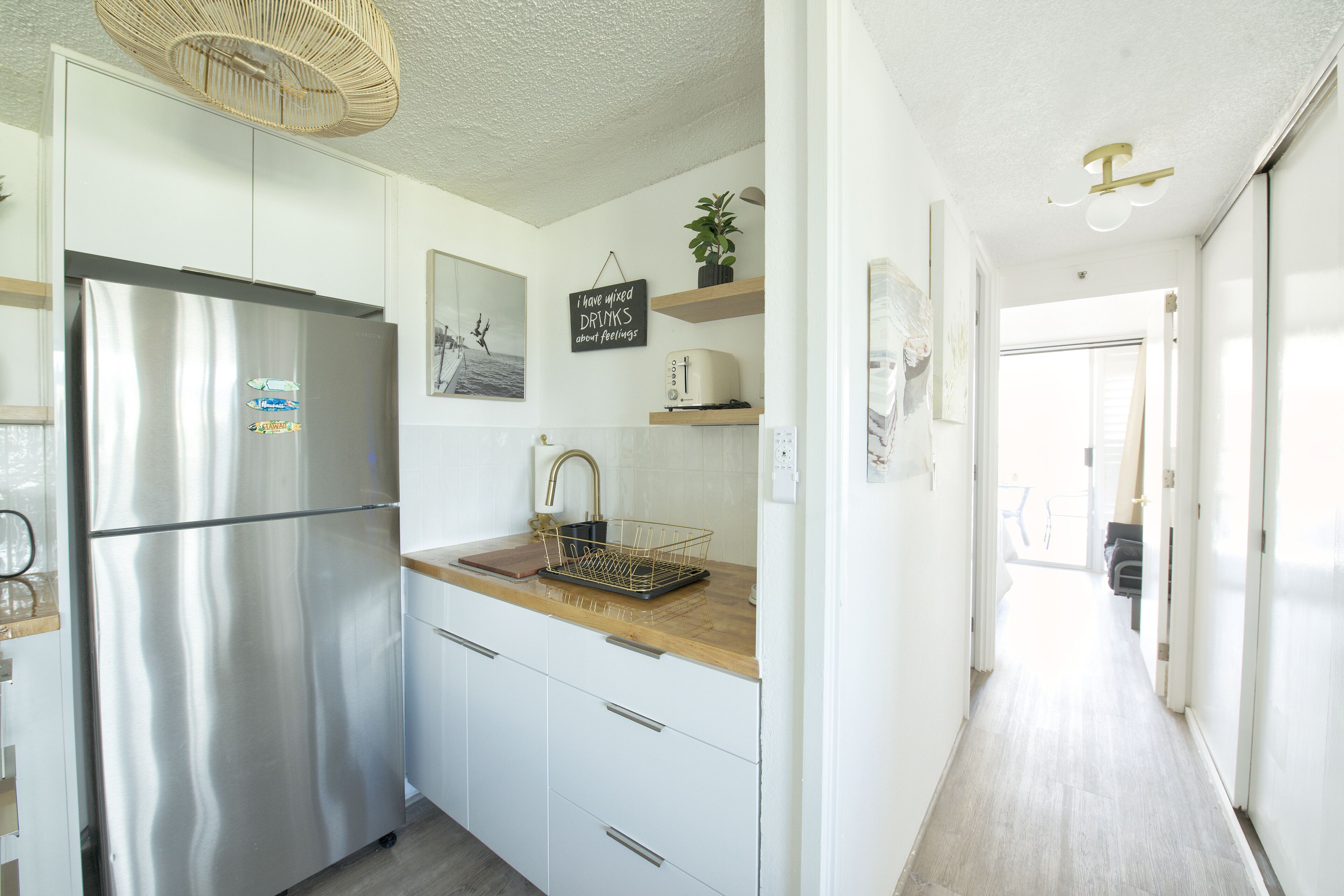 A modern kitchen with a stainless steel refrigerator, wooden countertop, and white cabinetry.