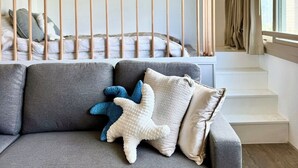A modern bedroom with a grey sofa, a bed with a wooden headboard, and a large window with curtains. - Honolulu Central Waikiki luxury High With Views & Beach (Honolulu)