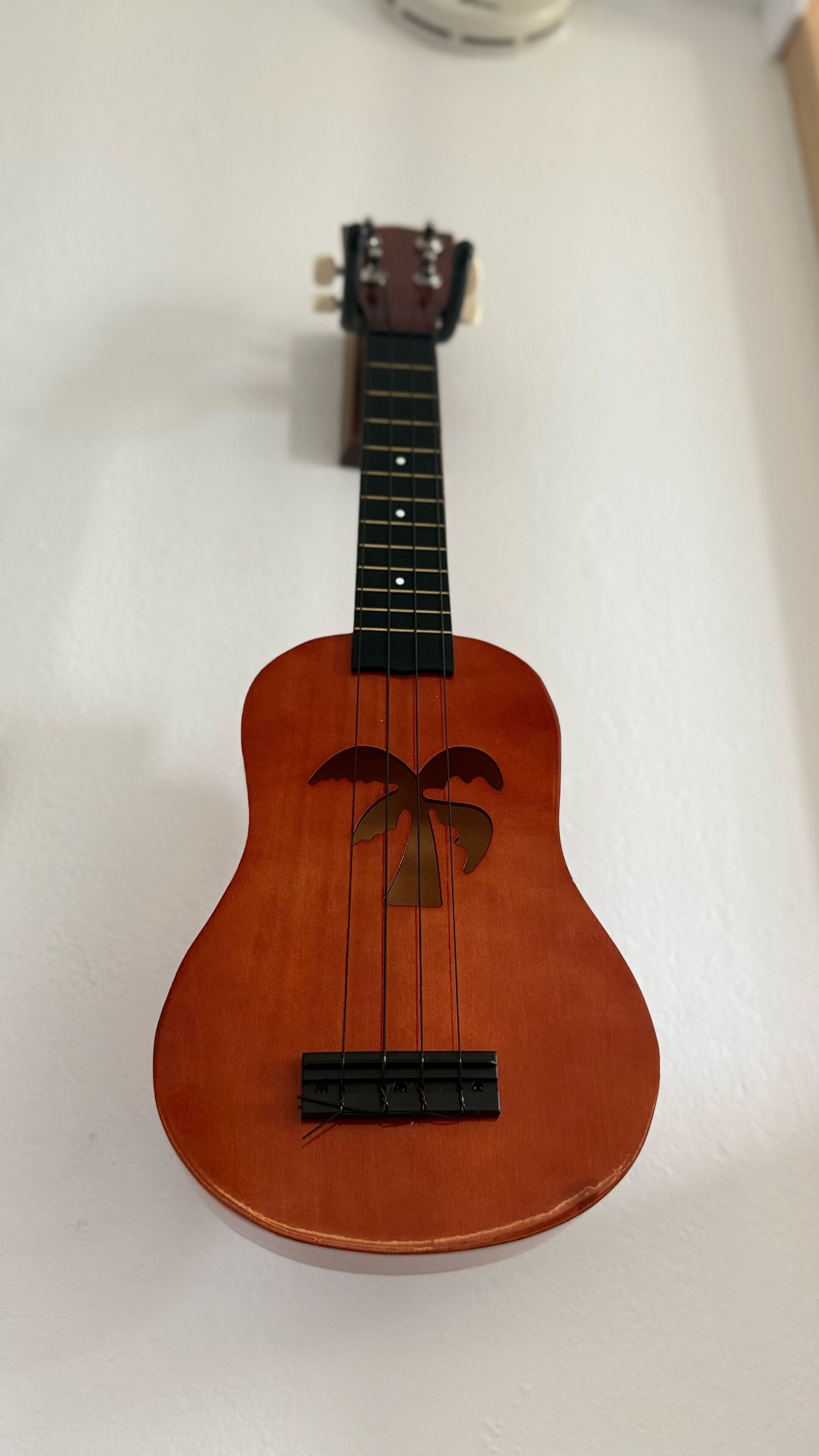 A ukulele with a decorative bow on the sound hole, placed on a white surface.