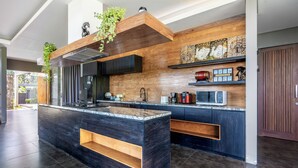 Eine moderne Küche mit dunklen Holzschränken, einer zentralen Kochinsel und einer eingebauten Mikrowelle.