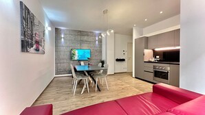 Una cocina moderna con electrodomésticos de acero inoxidable, un comedor con mesa y sillas, y un sofá rojo.