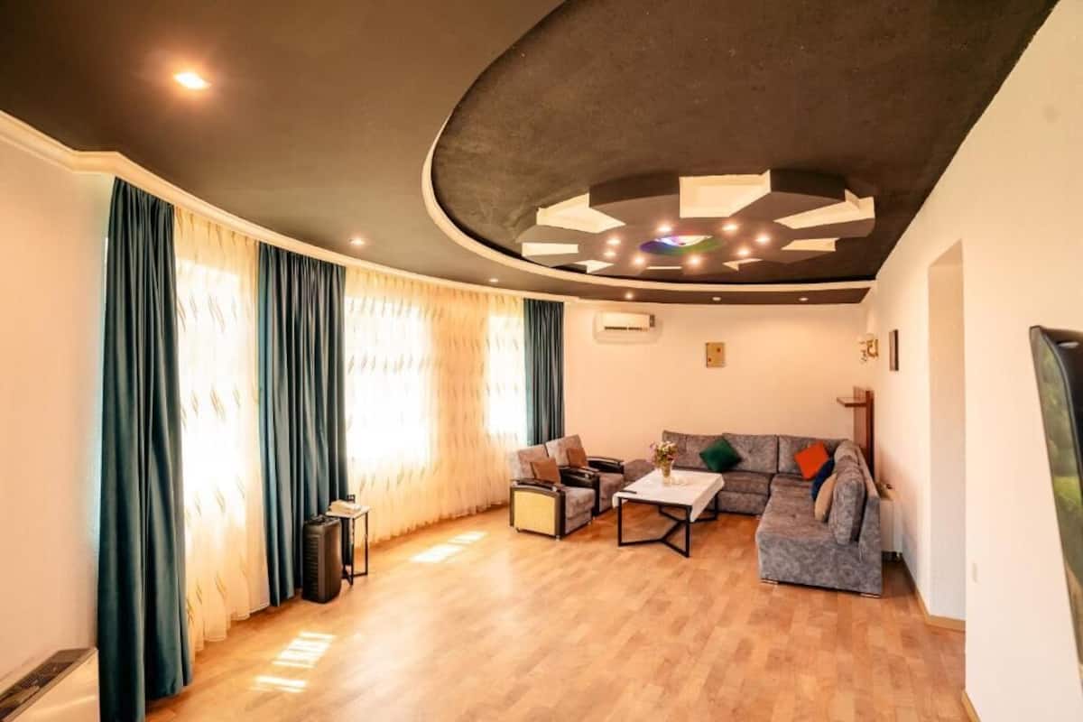 A modern living room with a curved ceiling, a sectional sofa, a coffee table, and a television.