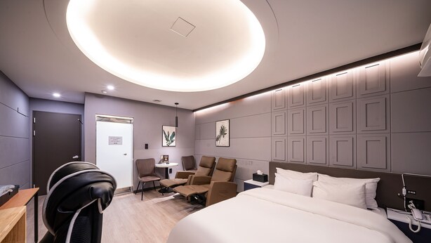 A modern hotel room with a large bed, a desk, a chair, and a small table. - Hotel Bosco Incheon (Incheon)