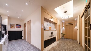 A hotel reception area with a reception desk, framed artwork on the walls, and a tiled floor. - Hotel Bosco Incheon (Incheon)