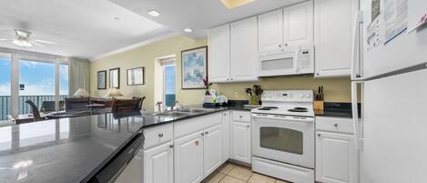 A modern kitchen with white cabinets, a black countertop, and a built-in oven.